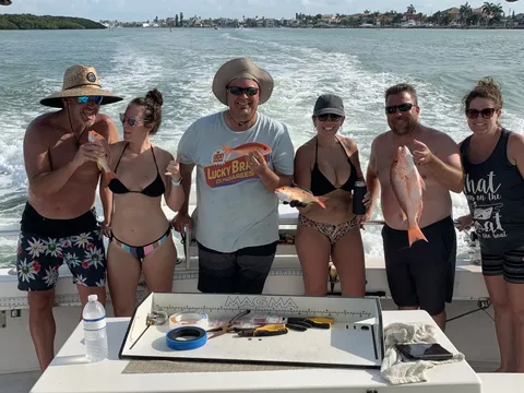 A group of six on the back deck with the day’s catch, the boat’s wake behind them