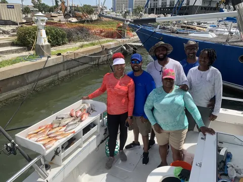 A group at the dock beside a table full of red snapper