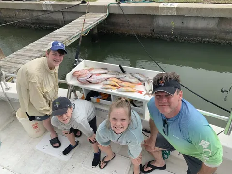 A family crouched by the fish box at the dock with the catch laid out