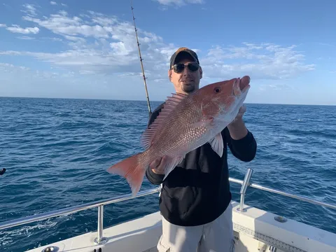 An angler offshore holding up a red snapper