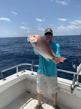 An angler on deck holding a red snapper against open water