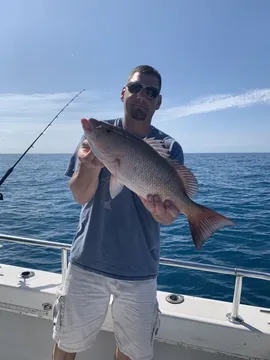 An angler offshore holding a large snapper