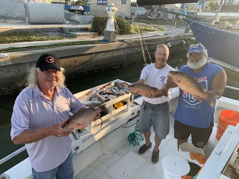 Three anglers at the dock showing off fish over the cleaning table