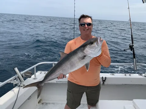An angler offshore holding a long silver fish