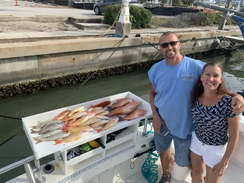Two anglers at the dock beside a table of snapper