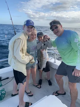 A family of four on deck offshore with their fish