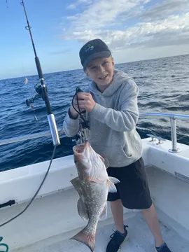 A young angler on deck holding up a fish