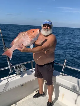 An angler on deck holding a large red snapper