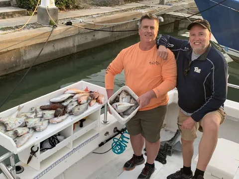 Two anglers at the dock behind the cleaning table and the catch