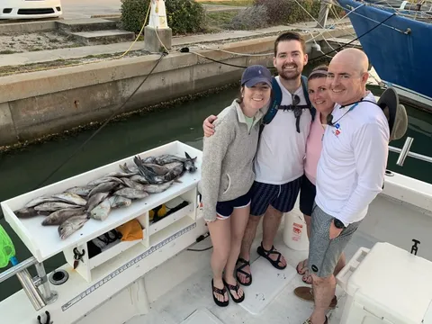 Four anglers at the dock beside a table of fish