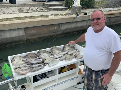 An angler at the dock standing over a table full of fish