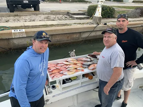 Three anglers at the dock with a table of red snapper