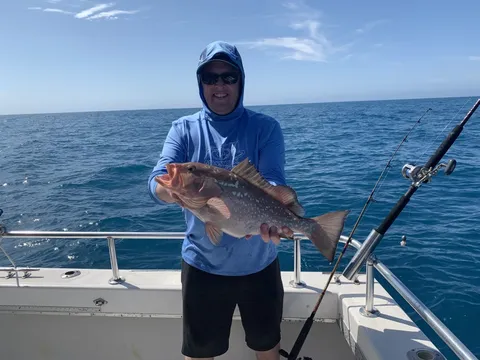 An angler offshore holding a snapper by the rail